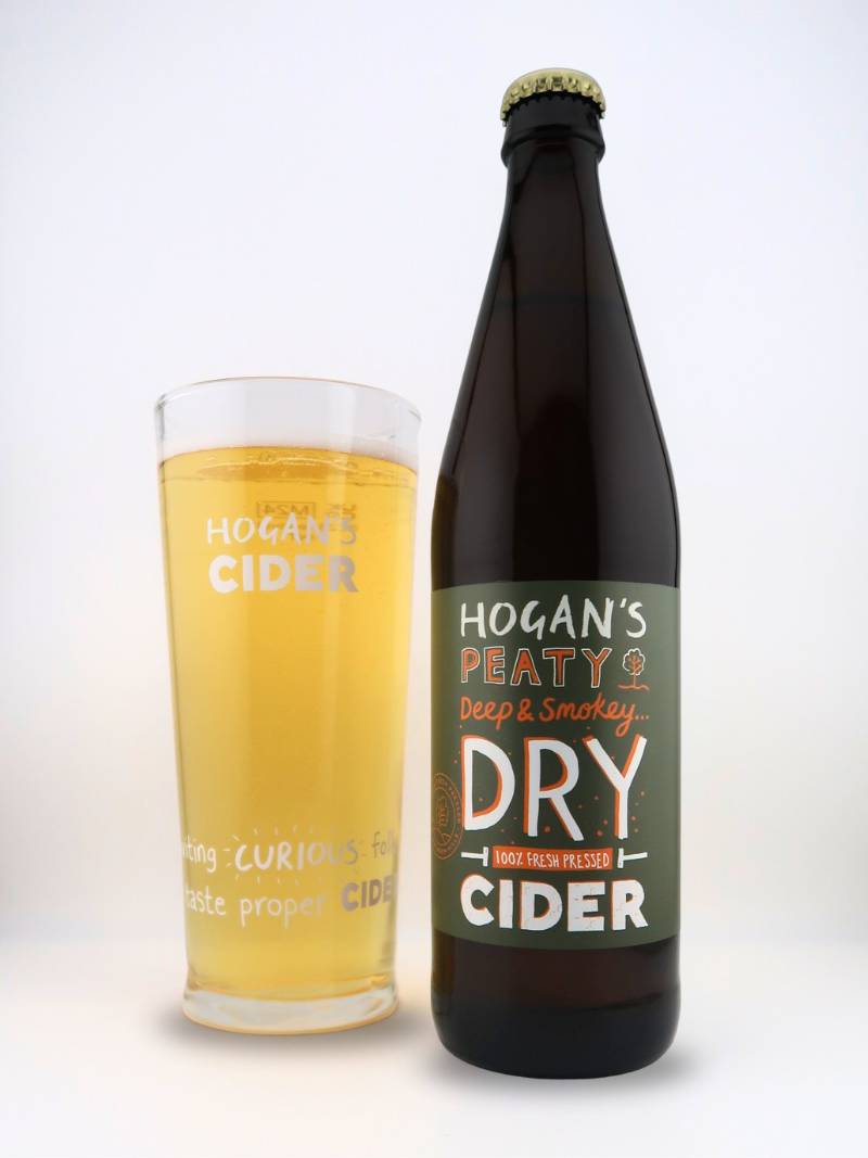 Hogan’s Dry Cider – deep and smoky craft cider bottle beside a branded pint glass filled with golden cider.