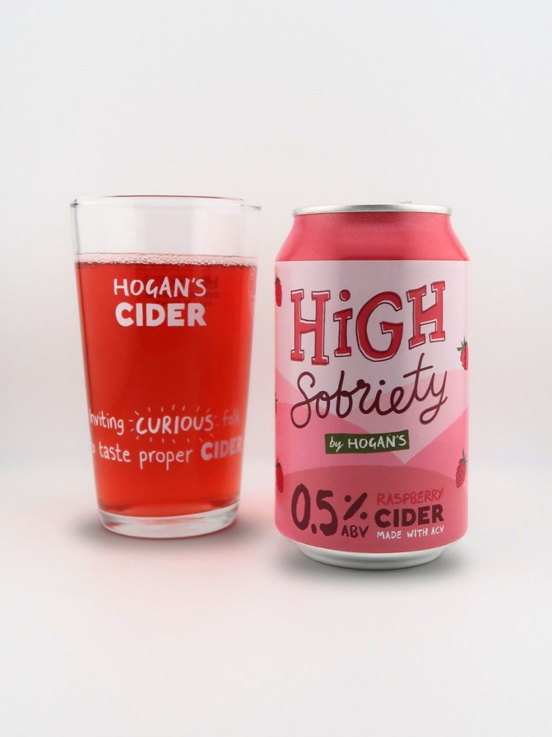 Hogan’s High Sobriety Raspberry 0.5% Cider – low-alcohol craft cider can beside a half-pint glass filled with vibrant pink cider.