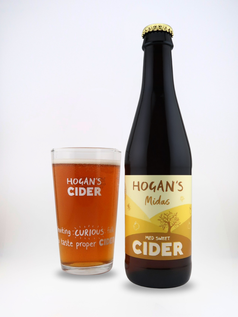 Hogan’s Midas medium sweet cider bottle with branded half-pint glass filled with amber cider.